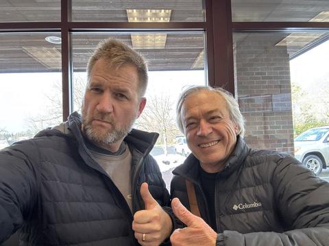 James and a friend in puffer jackets giving thumbs up