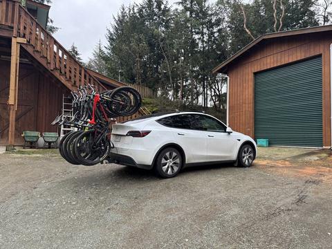 A white car with mountain bikes on a rear rack outside a barn