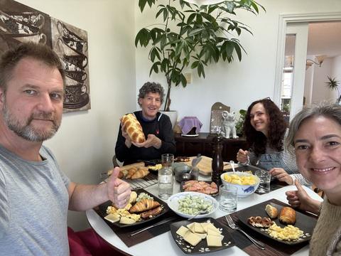 Friends around a table with bread, cheese and salads