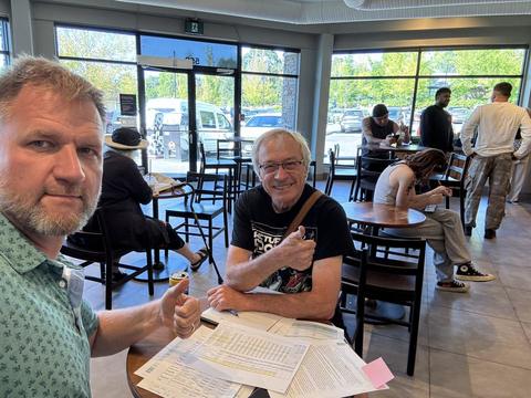 James and a friend at a cafe table covered in papers