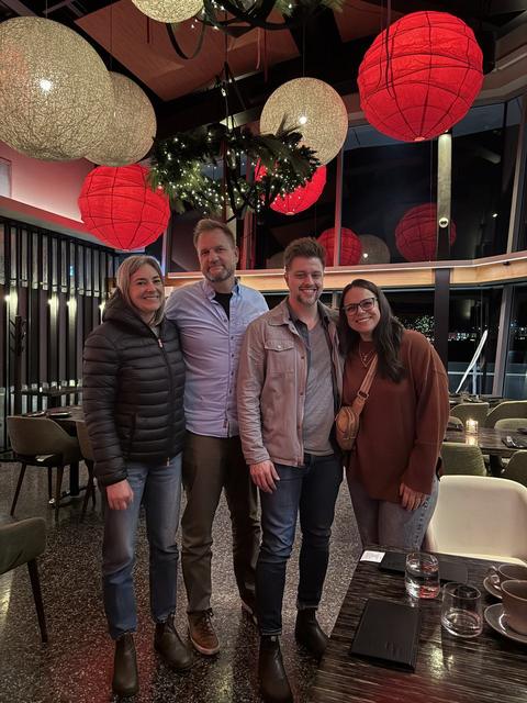 Four friends standing together under red paper lanterns in a restaurant