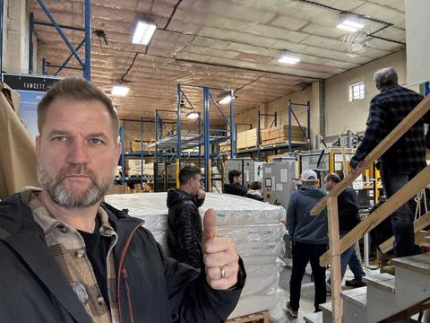 James giving a thumbs up in a busy warehouse