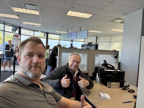 James and a colleague giving thumbs up at an office desk