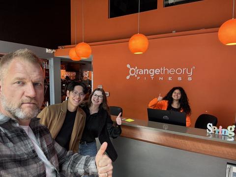 James with staff at the front desk of an Orangetheory Fitness studio
