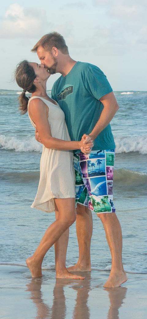 A couple kissing at the water's edge on a beach