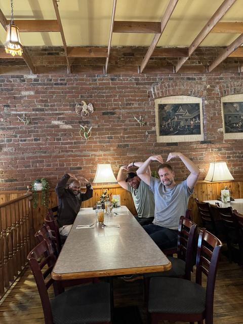 Friends making heart shapes with their hands in a brick-walled restaurant