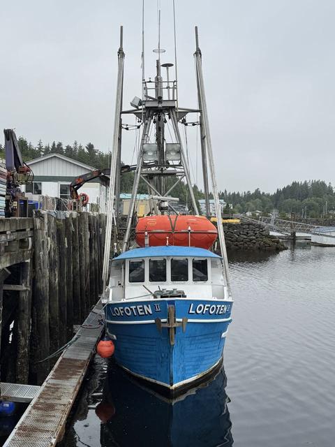The blue fishing vessel Lofoten moored at a wooden dock