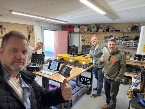 James and three people in a workshop with yellow equipment on the bench