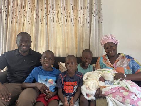 A family on a couch with three boys and a newborn baby